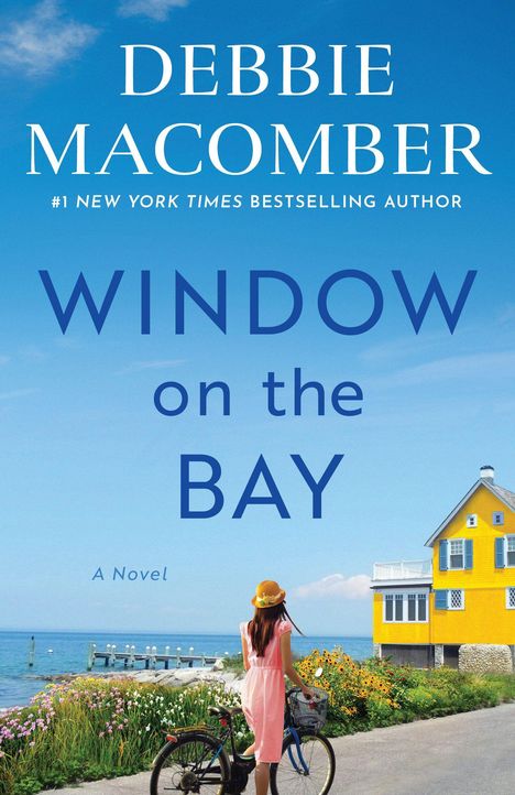 Titel: "Debbie Macomber: Window on the Bay". Frau in Hut neben Rad, blickt aufs Meer. Gelbes Haus, blauer Himmel.