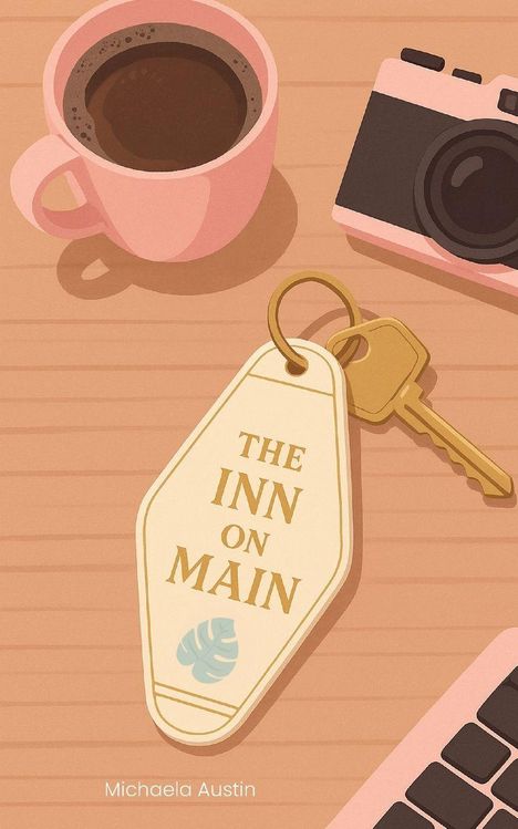 „THE INN ON MAIN“ auf einem Schlüsselanhänger. Daneben eine rosa Kaffeetasse, Kamera und Computertastatur.
