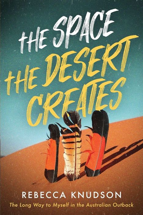 „The Space the Desert Creates“, Rebecca Knudson. Darunter bunte Federn auf sandigem Untergrund.