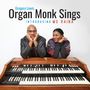 „Gregory Lewis Organ Monk Sings Introducing Ms Raina“; Zwei Personen lehnen an einer Hammond-Orgel und lächeln freundlich.