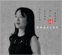 Texte: HELEN SUNG BIG BAND, ORACLES. Eine Frau mit dunklen langen Haaren lächelt. Hintergrund hat asiatische Zeichen.