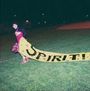 Das Bild zeigt eine Person auf einem Sportfeld, die ein gelbes Banner mit der Aufschrift "SPIRIT!" über den Rasen zieht.