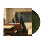 Zwei Männer in Anzügen in einem Klassenzimmer, einer sitzt am Lehrerpult, der andere lehnt an der Tafel. Vinyl-Schallplatte dabei.