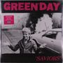 Der Text lautet "GREEN DAY" und "SAVIORS". Ein Junge steht vor einem brennenden Auto und lächelt.