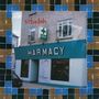 Texte: "sebadoh", "HARMACY", "O'Dwyer's". Eine Apotheke in einem hellgrauen Gebäude mit einem grünen Kreuz als Logo.