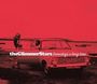 „theGlimmerStars Someday's a long time“ in weißem Text auf rotem Hintergrund. Ein altes Auto am Ufer.