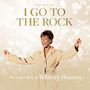 Text: "I Go to the Rock", "The Gospel Music of Whitney Houston". Frau in beige Jacke mit erhobenen Händen, Hintergrund hell.