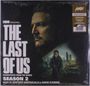 Texte: "HBO Original - The Last of Us - Season 2 - Music by Gustavo Santaolalla & David Fleming".  
Gesicht und bewaffnete Person im Hintergrund.