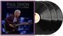 "PAUL SIMON: THE QUIET CELEBRATION CONCERT". Ein Mann spielt Gitarre, daneben mehrere Schallplatten.