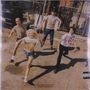 Unter dem Bild stehen die Worte "Amyl and the Sniffers" und "Cartoon Darkness". Vier Personen rennen dynamisch auf einer Straße.