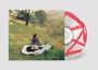Eine CD mit rotem, stilisiertem "A" darauf. Foto von einer Person auf einer Decke in einer grünen Wiese.