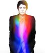 Ein schwarz-weiß Foto einer Person in einem Anzug, überlagert von hellen Regenbogenfarben in der Mitte.