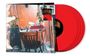 Ein Schreibtisch mit Stuhl, umgeben von Musikgeräten, Pflanzen; daneben drei rote Schallplatten.