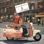 "Have Guitar Will Travel wire BO DIDDLEY." Ein Mann in roter Jacke fährt einen Roller mit einer Gitarre.