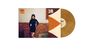 Text: „Sienna Spiro, Visitor.“ Eine Frau in einem schwarzen Kleid steht vor einer gemusterten Wand. Daneben eine goldene Vinyl.