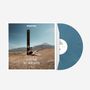 "SO IST DAS MIT DEM GLÜCK", darüber "MONTEZ". Jemand lehnt an einem Holzpfahl in einer trockenen Landschaft mit Bergen.