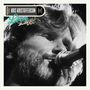 „Kris Kristofferson Live from Austin TX“. Nahaufnahme eines bärtigen Mannes, der in ein Mikrofon singt. Schwarz-Weiß-Fotografie.