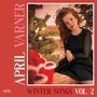 "APRIL VARNER" und "WINTER SONGS VOL. 2". Eine Person in festlicher Umgebung neben einem Weihnachtsbaum.