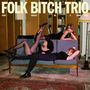 Text: "FOLK BITCH TRIO. NOW WOULD BE A GOOD TIME." Drei Personen posieren in einem Wohnzimmer auf einem Sofa.