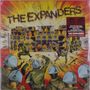 „THE EXPANDERS“ steht in großen Buchstaben. Illustration von Polizisten und Musikern vor einem Turm aus Lautsprechern.