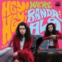 Auf Schrift steht: "HEY! HEY! WE'RE BANDA LOS." Zwei Personen mit langen Haaren in roten Anzügen lehnen an einem Auto.