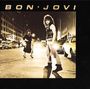 "BON JOVI" steht oben. Eine Person mit lockigem Haar steht selbstbewusst auf einer nächtlichen Stadtstraße.