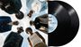 Sechs Männer in stilvoller Kleidung schauen in die Kamera. Daneben zwei Schallplatten mit Texten und einem blauen Label.