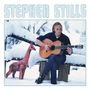 "STEPHEN STILLS" steht oben. Ein Mann spielt Gitarre im Schnee, sitzend auf einer Bank, neben einer bunten Giraffe.