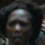 Unschärfe zeigt eine Person und Menschen im Hintergrund. Keine erkennbaren Texte oder Details zu sehen.