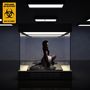 Oben links steht „ROXANNE de BASTION HERE LIES HUMAN“ mit einem Biohazard-Symbol. Person kniet in einem gläsernen Kasten.