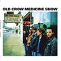 Text: "OLD CROW MEDICINE SHOW", "BIG IRON WORLD", Songtitel auf einem Schild. Fünf Männer stehen vor einem Schaufenster.