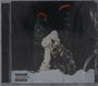 "Parental Advisory Explicit Content." Bild zeigt zwei vermummte Figuren, die sich umarmen, vor beleuchteten Hochhäusern bei Nacht.