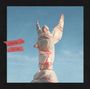 Text: "DOWNWARD (2)" und "DELUXE". 
Eine Statue, in Plastik und rotem Band eingewickelt, mit erhobenen Armen vor blauem Himmel.