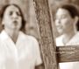 Text: "ficufresche voci dalle toraglie". Zwei unscharfe Personen hinter rustikalem Holzzaun in Sepia-Ton.