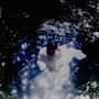 Ein Mensch in einem hellen Gewand, umgeben von schimmerndem Licht im Wasser, erzeugt eine traumhafte, geheimnisvolle Atmosphäre.