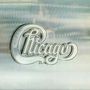 "Chicago" in geschwungener Schrift vor einem metallischen Hintergrund. Logo-Stil mit eleganter Typografie.