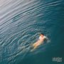 Text: "saturdays at your place". Eine Person schwimmt im Wasser, umgeben von sanften Wellen.
