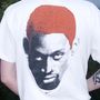 Ein weißes T-Shirt zeigt ein pixelartiges Porträt mit orangefarbenen Haaren und einem kleinen Nike-Logo darunter.