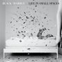 "BLACK/MARBLE LIFE IN SMALL SPACES" Oben, Konfetti wirbelt um liegende Person mit Buch auf Bett.