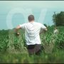 Großes, halbtransparentes "OV". Zwei Männer im Feld, der vordere im weißen T-Shirt läuft, der hintere schaut.