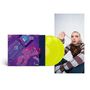 Ein gelbes Vinyl, ein illustratives Albumcover mit Person auf Sofa, daneben eine Frau mit gestreiftem Pullover kauend.