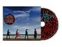 „U2 Carnaval de Luz“, CD und Cover. Vier Personen gehen am Strand entlang, Himmel und Meer im Hintergrund.