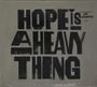 Text: "HOPE IS A HEAVY THING", kleinerer Text oben rechts: "The new record from JOY OLADOKUN". Schwarze Schrift auf grauem Hintergrund.