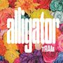 Text: "alligator TRAM". Hintergrund: Bunte Blumen in lebendigen Farben.