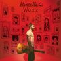 Text oben: "étincelle 2 Waxx". Ein Mann steht in einem Raum mit gezeichneten Porträts auf den Wänden. Er hält eine Gitarre.