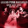 „Grand Funk Railroad, Madison Square Garden, New York 1972.“ Rötliche Konzertszene mit drei Musikern, einer mit Gitarre.