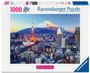 "1000 Ravensburger Puzzle. Beautiful Skylines." zeigt eine Stadt bei Sonnenuntergang mit einem beleuchteten Turm und einem Berg im Hintergrund.