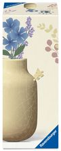 „Ravensburger“ und „3D Puzzle“ auf Verpackung. Vase aus Puzzleteilen mit blau-lila Blumen-Illustration oben.