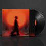 Vorne eine Silhouette vor orange-rotem Licht, rechts eine Vinyl-Schallplatte teilweise sichtbar.