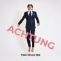 Text: "ACHTUNG" in großem Rot darüber "TINO SCHULTER". Ein Mann im Anzug schwebt mit nackten Füßen vor weißem Hintergrund.